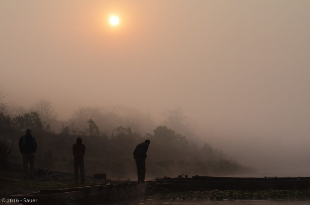 Männer und Flöße im Nebel bei Sonnenaufgang