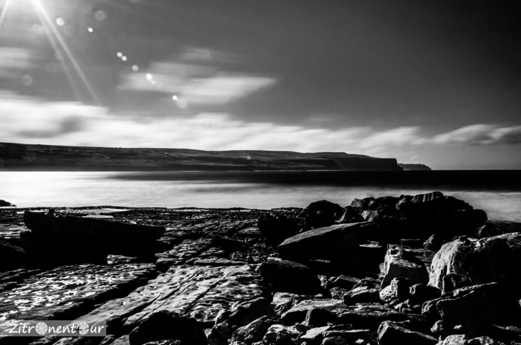 Langzeitbelichtung der wilden Felsenküste in Doolin. Im Hintergrund die Cliffs of Moher