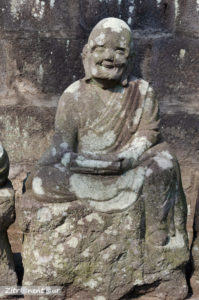 Statue eines lächelnden Buddha im Garten Gohyaku Rakan